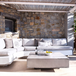 outdoor sitting area, wines and fruits on the table at villa ammolite in mykonos