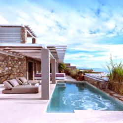 swimming pool with panoramic view of mykonos, an outdoor sitting area with beautiful sundbeds at villa ammolite in mykonos