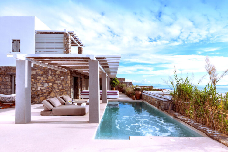 swimming pool with panoramic view of mykonos, an outdoor sitting area with beautiful sundbeds at villa ammolite in mykonos