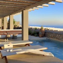 swimming pool with panoramic view of mykonos, an outdoor sitting area with beautiful sundbeds at villa ammolite in mykonos