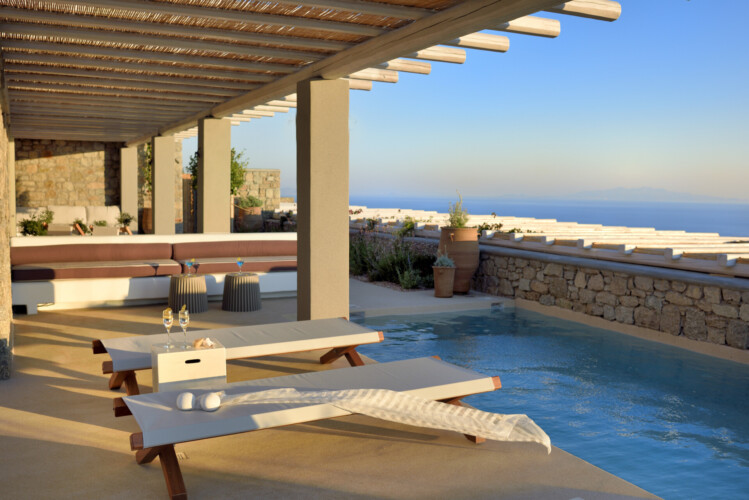 swimming pool with panoramic view of mykonos, an outdoor sitting area with beautiful sundbeds at villa ammolite in mykonos