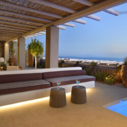 sunset with drinks at the outdoor sitting area from villa ammolite in mykonos, swimming pool with lights and a gorgeous terrace